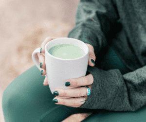 Woman sitting with a cup of matcha outside in the sunshine. 