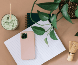 Flatlay of cell phone face down, matcha drink and journal. 