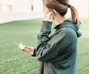 Woman putting in earbuds showing shes going to do some exercise for habits to improve mental health.