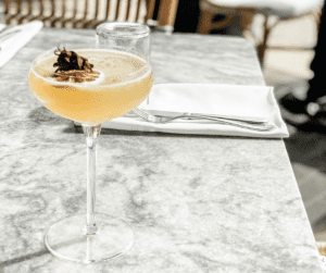 Image of an alcoholic beverage sitting on a table that is set at a resturant. 