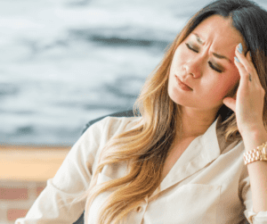 Image of a business woman leaning back in a chair and holding her head in pain of a migraine. 