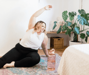 Image of woman doing some gentle stretches at home. Showing what are the symptoms of fibro fog and how to help reduce them. 