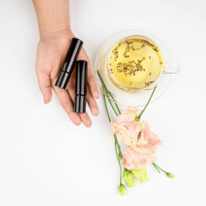 Image of hand holding 2 essential oil blends roller bottles. 