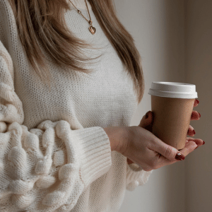 Image of woman holding coffee cup as drinking to avoid with migraine that are dehydrating. 