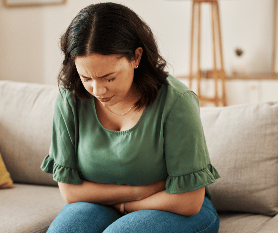 Image of woman clenching her stomach stress cause bloating. 