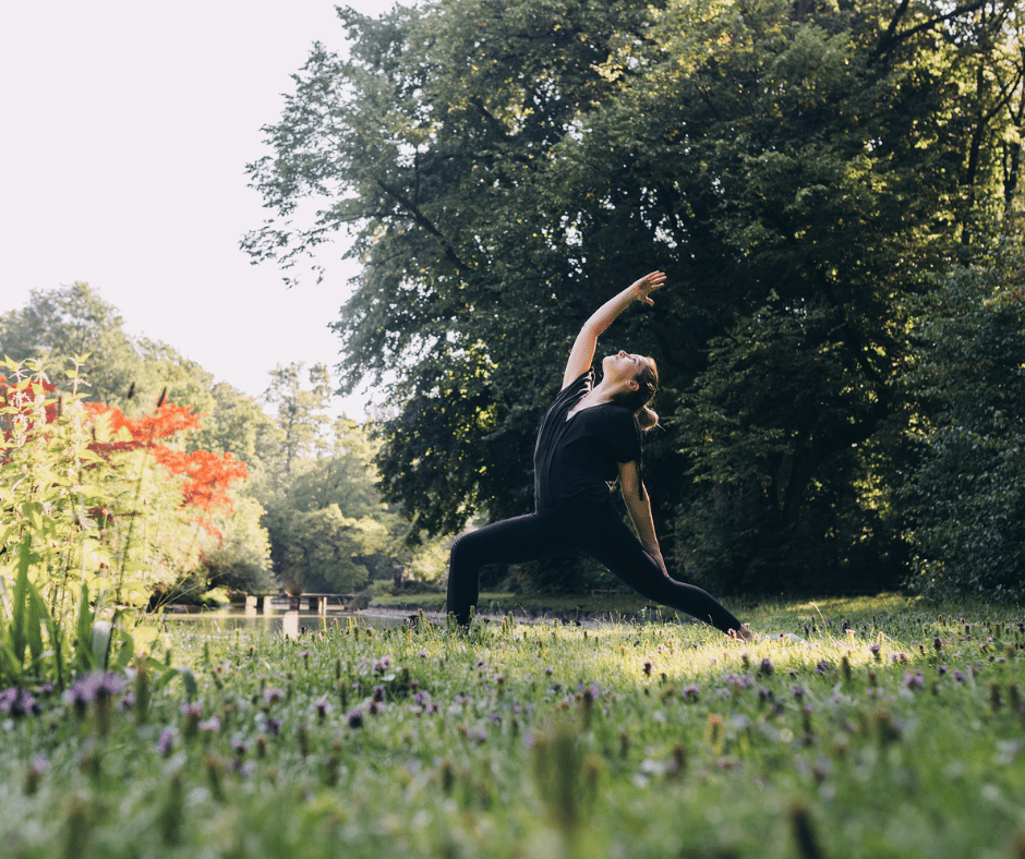 Image of woman doing yoga outside to help with stress cause bloating. 