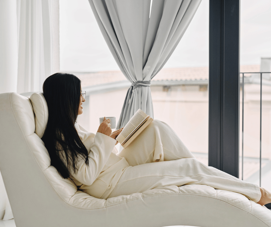 Image of woman lounging and reading while drinking a coffee in the morning. 