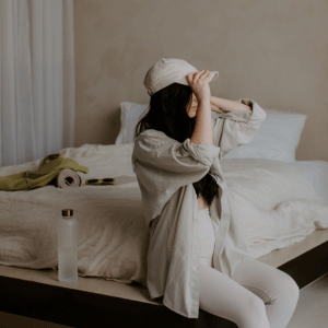 Woman sitting on edge of bed getting ready for gentle at home stretching to help with can fibromyalgia cause shortness of breath. 