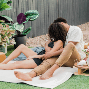 Image of a couple snuggled up on a blanket in a back yard as a simple Dating with a chronic illness idea. 