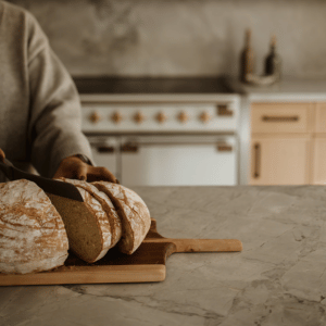 Image of a woman slicing a loaf of homemade break on a cutting board.